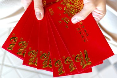 Kırmızı zarf, kırmızı paket, Hong Bao Hongbao 'yu tutan eller altın Fu sembollü Angpao, bereketi, şansı, refahı ve Ay' ın yeni yılını simgeliyor.