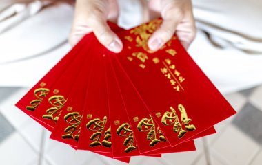 Kırmızı zarf, kırmızı paket, Hong Bao Hongbao 'yu tutan eller altın Fu sembollü Angpao, bereketi, şansı, refahı ve Ay' ın yeni yılını simgeliyor.