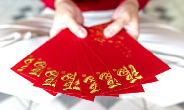 Kırmızı zarf, kırmızı paket, Hong Bao Hongbao 'yu tutan eller altın Fu sembollü Angpao, bereketi, şansı, refahı ve Ay' ın yeni yılını simgeliyor.