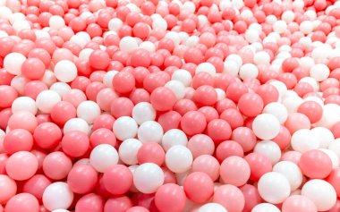 Oyuncak top, pembe ve beyaz top yoğun bir şekilde top havuzunu dolduruyor, top havuzunda plastik top, çocuk teması ve eğlence için parlak, neşeli, neşeli bir ortam yaratıyor.