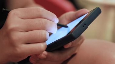 Akıllı telefon dokunmatik ekranına stil kullanan ya da yazan eller. Yakın plan. Dijital teknoloji kavramı, çevrimiçi çalışma, iletişim ve modern mobil yaşam tarzı