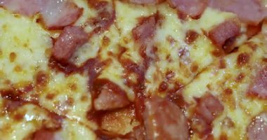 Eritilmiş peynirli pastırmalı pizza, yakın plan. Lezzetli fast food konsepti popüler İtalyan usulü pizza sosunu çıtır domuz pastırması ve erimiş peynir dokusuyla gösteriyor.