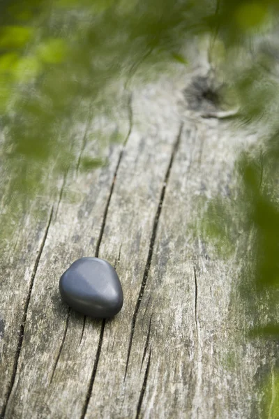 Pietra basaltica a forma di cuore su legno intemperie — Foto Stock