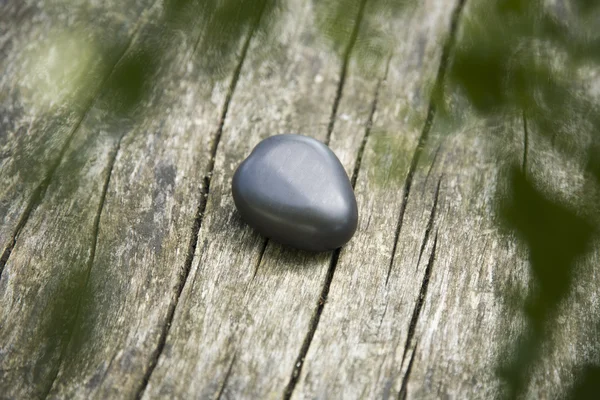 Herzförmiger Basaltstein auf verwittertem Holz — Stockfoto