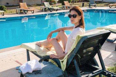 Yüzme havuzunda dinlenen genç ve seksi bir kadın. Seksi, güzel, zayıf kadın tatil yerinin tadını çıkar.