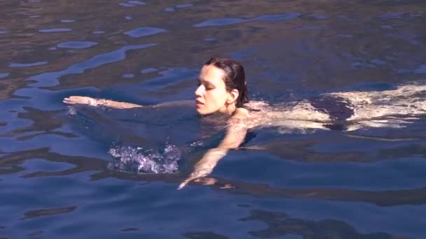 地中海の深い静かなターコイズブルーの海で泳ぐ魅力的な若い女性 スローモーション映像 — ストック動画