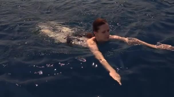 地中海の深い静かなターコイズブルーの海で泳ぐ魅力的な若い女性 スローモーション映像 — ストック動画