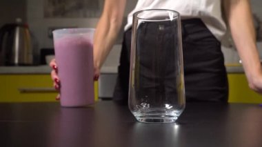 Kadın bardağa meyve püresi döküyor. Sağlıklı milkshake, muzlu smoothie..