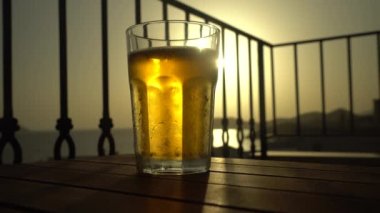 Gün batımında Bardakta Bira İçen Köpükler masada. Soğuk yaz içeceği konsepti.