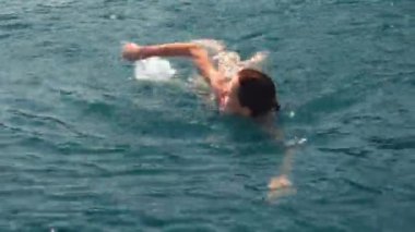 Akdeniz 'de sakin turkuaz sularda yüzen çekici genç kadın, yavaş çekim görüntüleri.