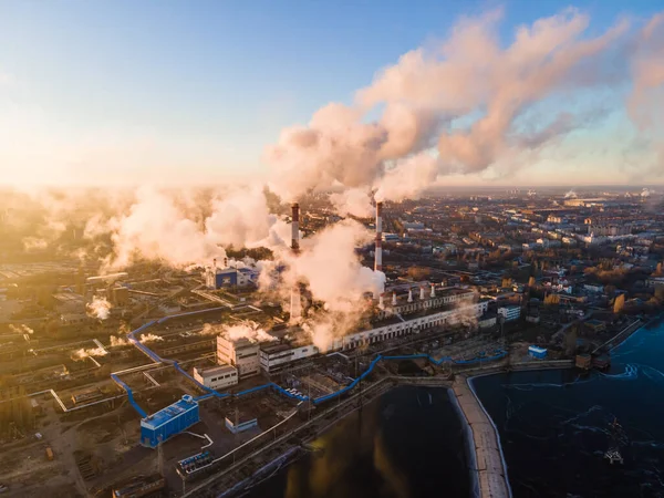 Factory chimneys producing smoke at sunrise, aerial view. Concept of air pollution, environment and ecology crisis, climate change, global warming