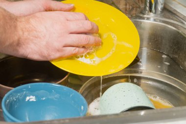 Erkekler el yıkama bulaşıkları, sarı tabaklar, evdeki mutfakta sünger..