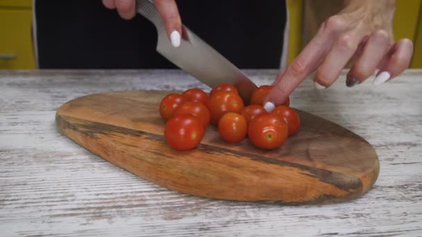 女性は 健康的な野菜サラダを準備家庭用キッチンで木製ボード上の鋭いナイフで新鮮なトマトをカット — ストック動画