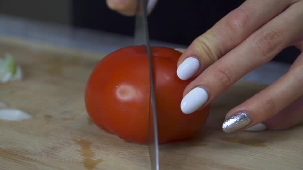 Mujer corta un tomate maduro en una tabla de cortar de madera — Vídeo de stock