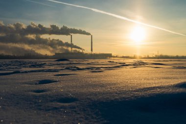 Gündoğumu arka planında sanayi bacasından duman çıkıyor. Enerji üretimi ve hava kirliliği endüstriyel boru sahnesi.