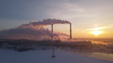 Sanayi bacasından yükselen duman gündoğumu gökyüzü arka planında.