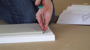 Bağımsız mobilya toplantısı. Kadın wirh tornavida vidayı çevirir, kapatır