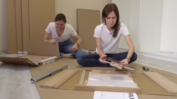 Mujeres Que Buscan Instrucciones Mientras Montan Los Muebles Relocation Estilo — Vídeos de Stock