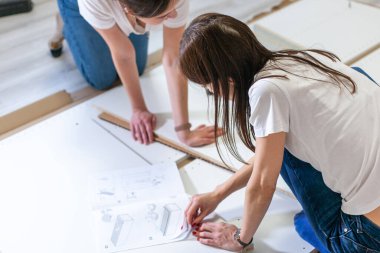 Kadınlar yeni evlerinde mobilya monte etme talimatlarını okuyorlar