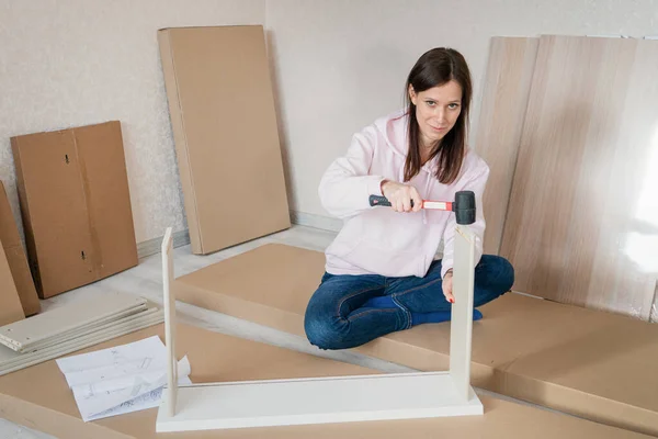 Self assembling furniture at home by woman using rubber mallet hammer.