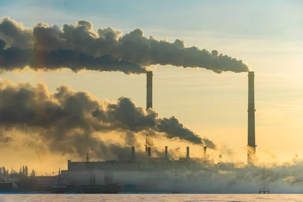 Environmental problem of pollution of air in cities. Smoking industrial zone factory chimneys. View of large plant with industrial pipes. Climate change and global warming concept