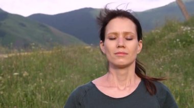 Gözleri kapalı bir kadın dağın tepesinde derin derin nefes alır. Meditasyon