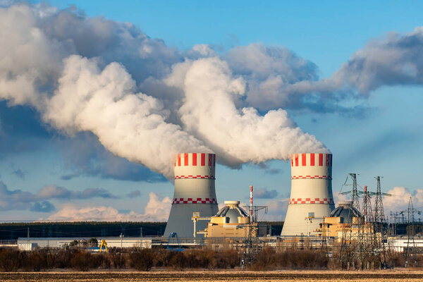 Загрязнение воздуха атомной электростанции охладительной башней паром атомной электростанции. Промышленная зона атомной энергетики с выбросом пара в атмосферу
