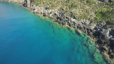 Turkuaz ve berrak deniz suyuyla kayalık kıyı şeridinin havadan görünüşü