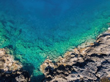 Güneşli bir günde turkuaz ve berrak deniz yüzeyi olan kayalık kıyı şeridi. Yaz tatili ve deniz yolculuğu..