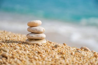 Deniz sahilinde dengede duran taşlar. Kumlu sahilde çakıl taşı piramidi. Bokeh 'le sabitlenmiş yığınlar ya da yığınlar halinde, yakın çekim. Zen dengesi, minimalizm, uyum ve barış