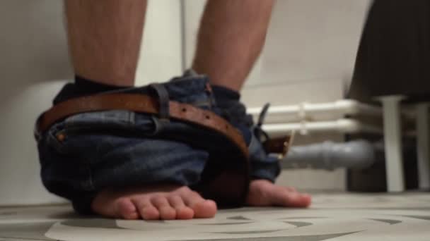 Man zittend op toilet zit kom met wc-papier — Stockvideo