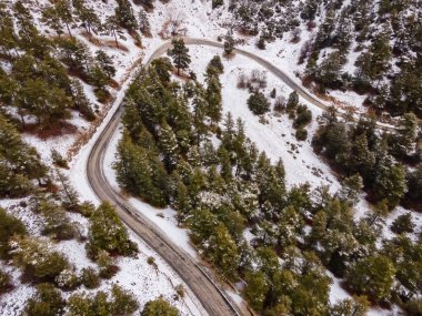 Yüksek dağlardaki asfalt yolun havadan görünüşü. Karlı kış ormanı
