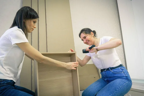 Self assembling furniture at home by women using rubber mallet hammer.