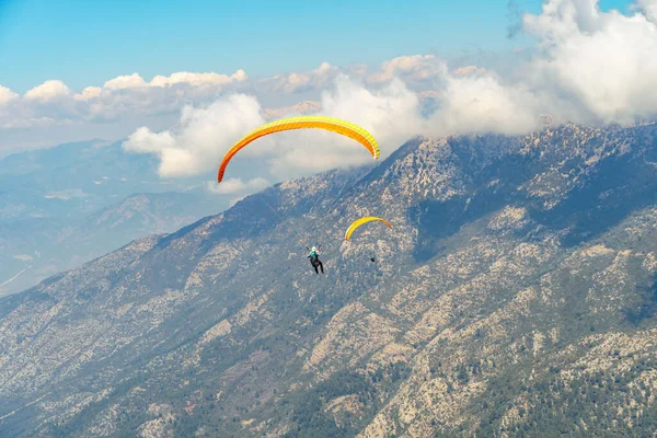 Paragliderler dağda gökyüzünde yamaç paraşütü yaparak süzülüyorlar. Dağlarda ekstrem spor