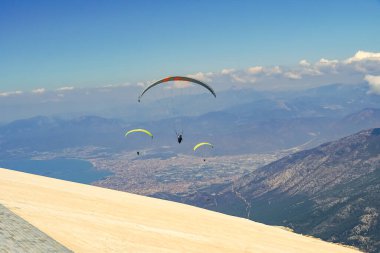 Paragliderler dağda gökyüzünde yamaç paraşütü yaparak süzülüyorlar. Dağlarda ekstrem spor