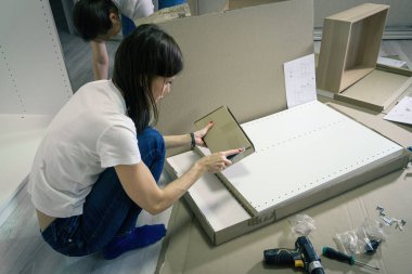 Millennial Woman mobilya montajı için kutuları açıyor. Mobilya ve DIY konsepti