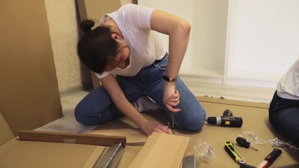 在家里的地板上组装平板家具的女人 通过网上商店购买家具 — 图库视频影像