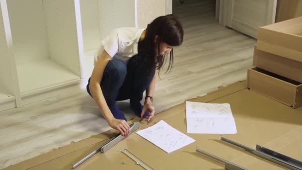 Тысячелетние женщины собирают мебель дома на полу — стоковое видео