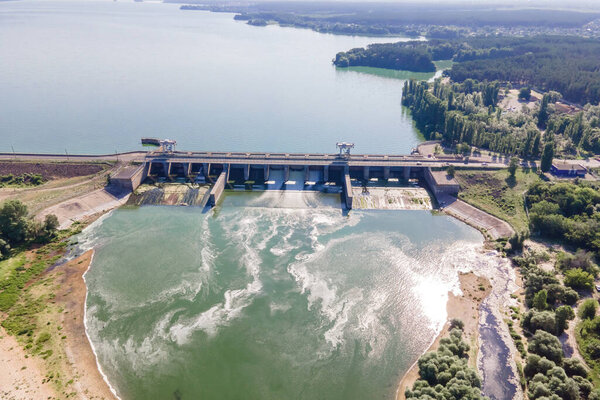 Плотина с текущей водой на гидроэлектростанции на водохранилище озера реки. Вид с воздуха