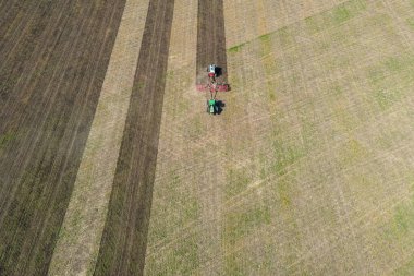 İlkbaharda tarla sürüp gübre üreten traktör..