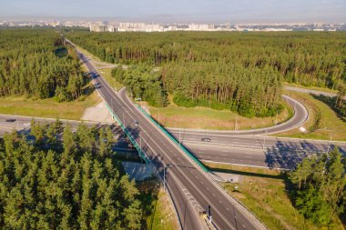 Şehir yakınlarındaki ormanda araba trafiğiyle kavşak noktası, hava manzarası.
