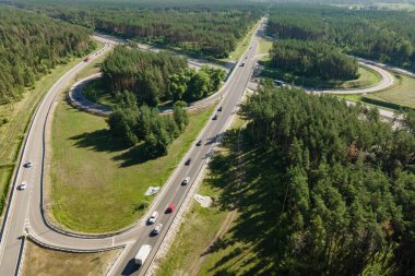 Şehir yakınlarındaki ormanda araba trafiğiyle kavşak noktası, hava manzarası.