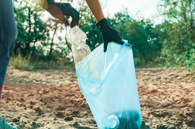 Kadın çöp torbasında plastik çöp topluyor. Çöpsüz gezegen konsepti. Doğa temizliği, gönüllü ekoloji yeşil kavramı