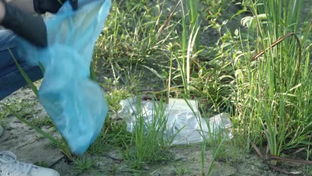 女人把一个塑料瓶放进垃圾袋 大自然中的垃圾收集 — 图库视频影像