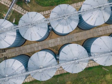 Hava sahasında metal silolar. Tahıl depolamak ve işlemek için büyük kaplar. Çiftlik arazisindeki gümüş tahıl asansörleri. Yukarıdan depolama tankı görünümü.