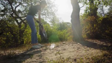 Kadın çöp torbasında çöp kutusu topluyor. Ormanda çöp toplama