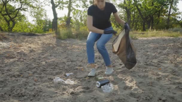 收集瓶子 穿着牛仔裤和白色运动鞋的年轻女子在森林里捡塑料瓶和垃圾 — 图库视频影像