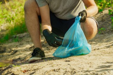 Gönüllü adam çöp torbasında çöp topluyor. Çöpsüz gezegen konsepti. Doğa temizliği, gönüllü ekoloji yeşil kavramı.