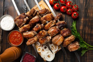 Izgara kuzu kaburgası, baharat ve sosla dolu bir şişin üstünde kesilmiş. Koyu ahşap masanın üstü.