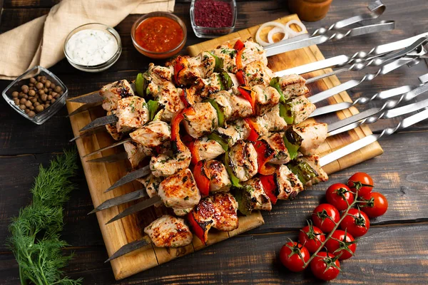 Turkey or chicken shish kebab on metal skewers with pepper tomatoes and onion on rustic wooden table background